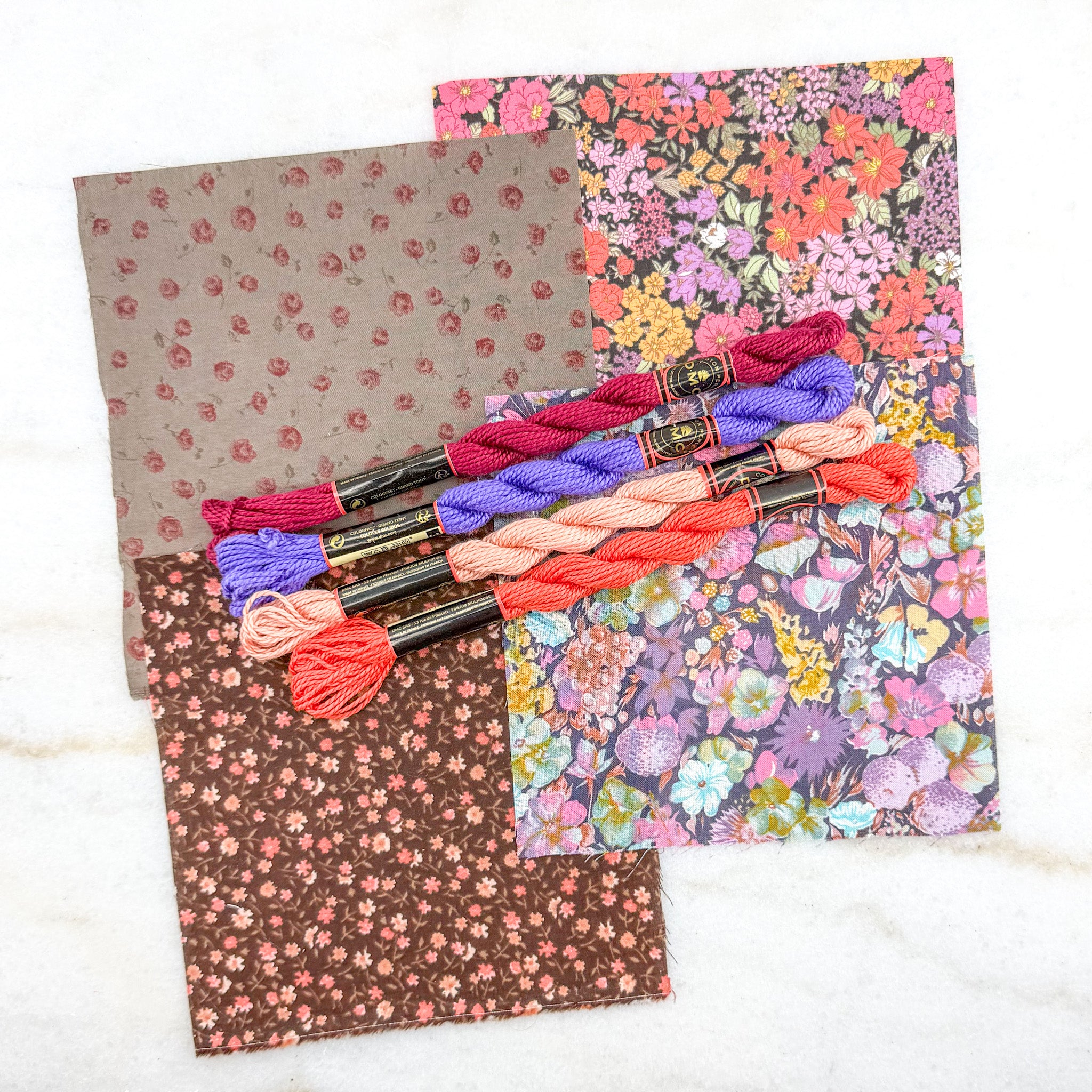Colorful embroidery floss spools and fabric samples on a white background