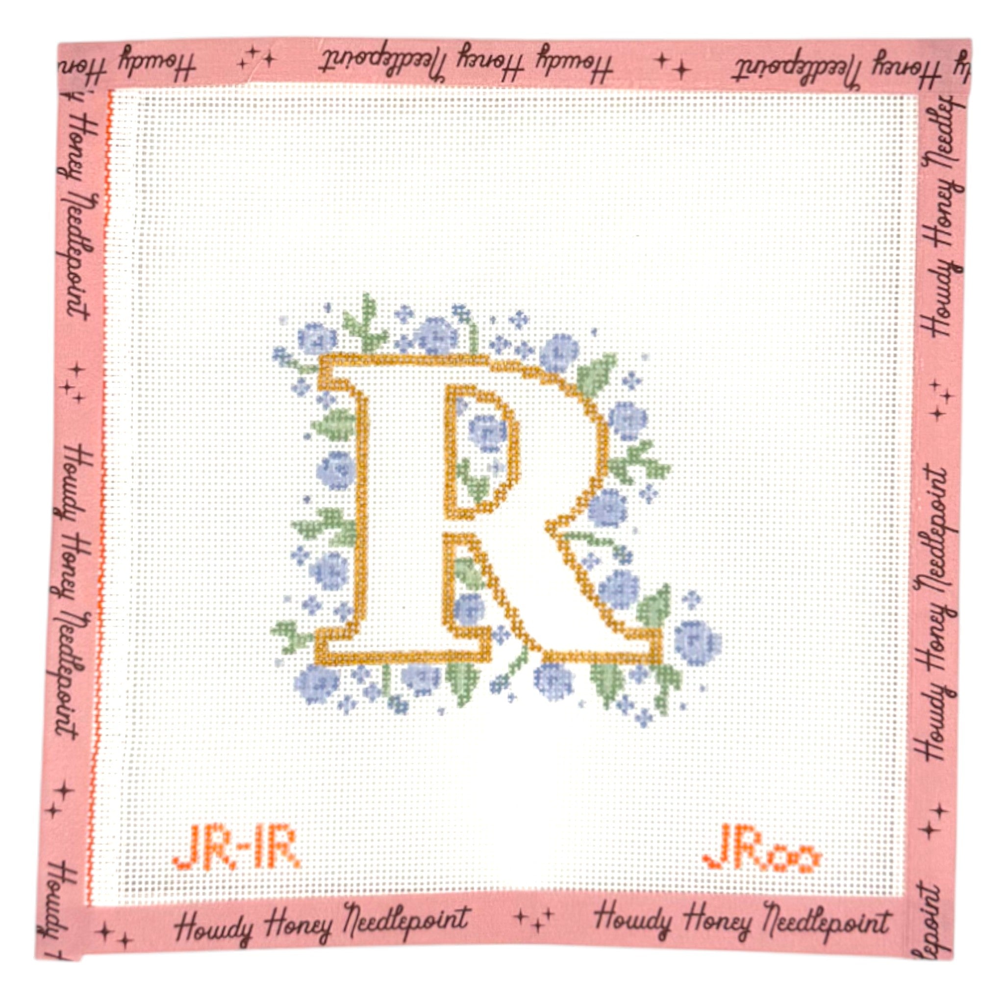 Cross-stitched letter 'R' with flowers on a white background, framed by pink border with text.