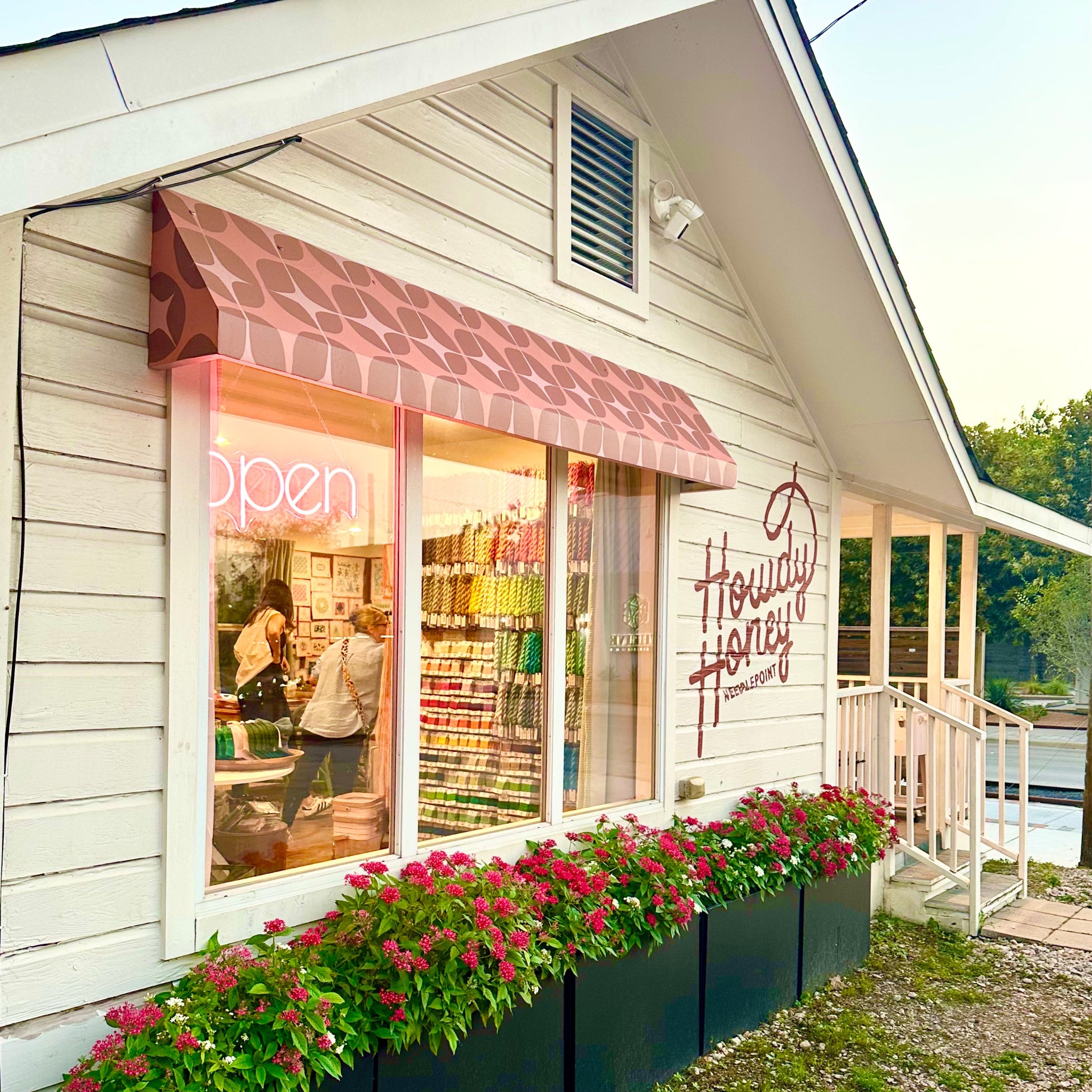 Storefront with 'Howdy Honey' sign, flowers, and 'open' sign.