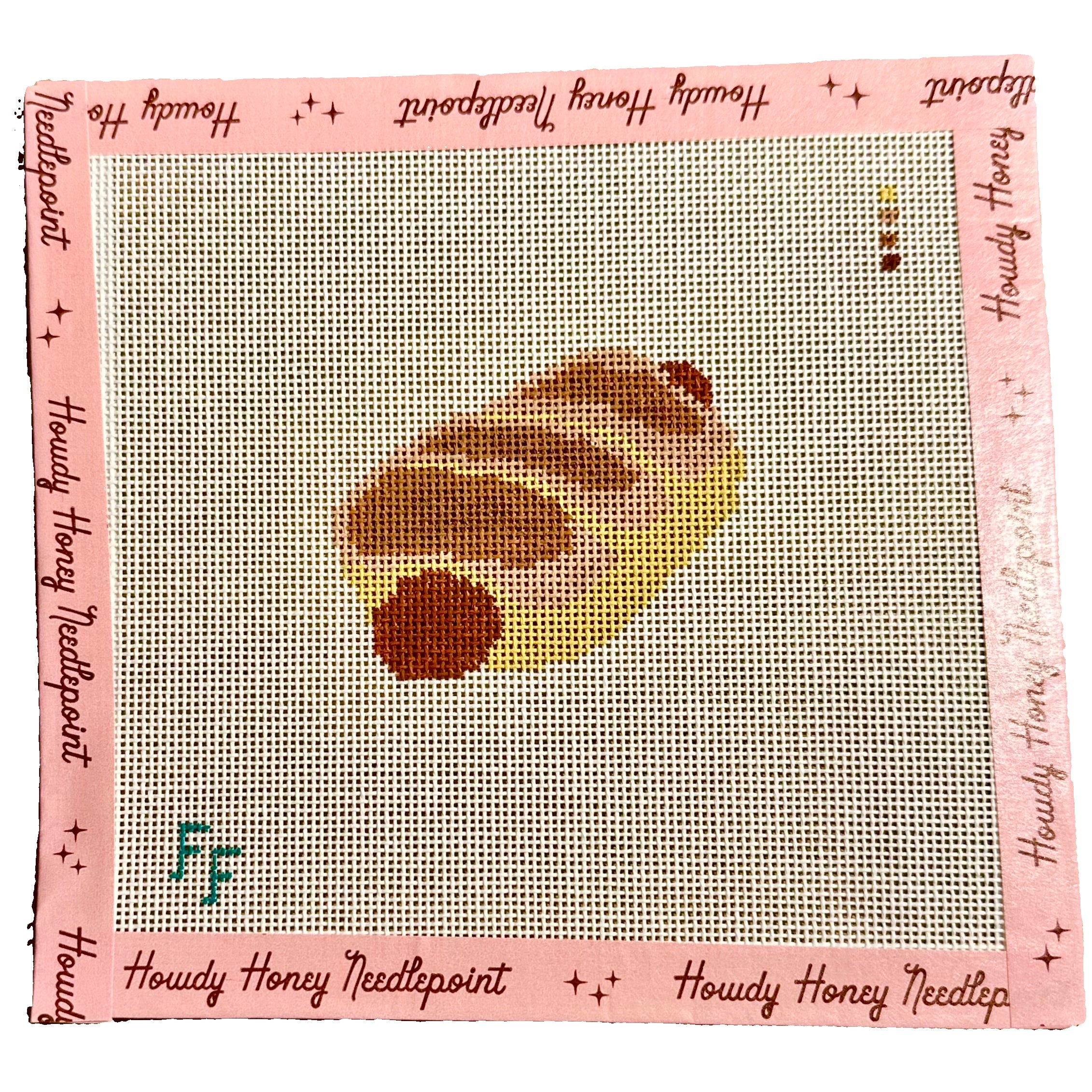 Howdy Honey Needlepoint canvas with a completed design of a honeycomb on a wooden surface.