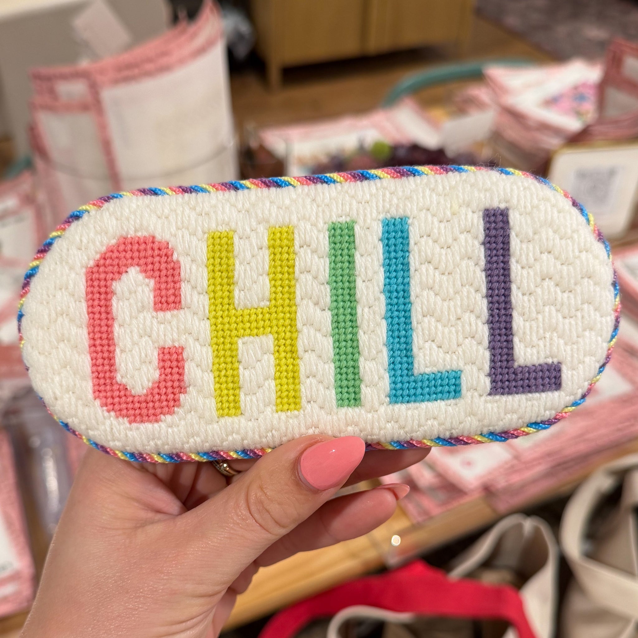 Colorful 'CHILL' pouch held by a hand with a blurred indoor background