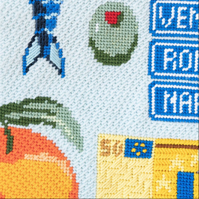 Cross-stitched design with fish, coral, and flags on a white background
