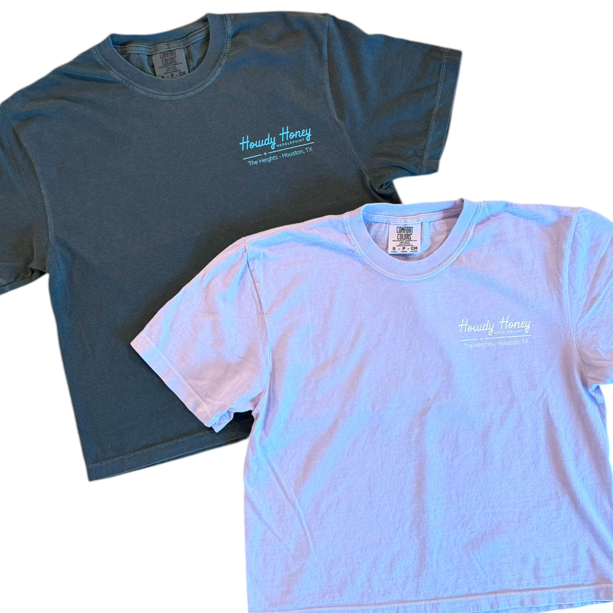 Two short-sleeve crewneck t-shirts shown overlapping on a white background. The top shirt is dark teal with a small light blue 'Honestly Honey' logo on the left chest.