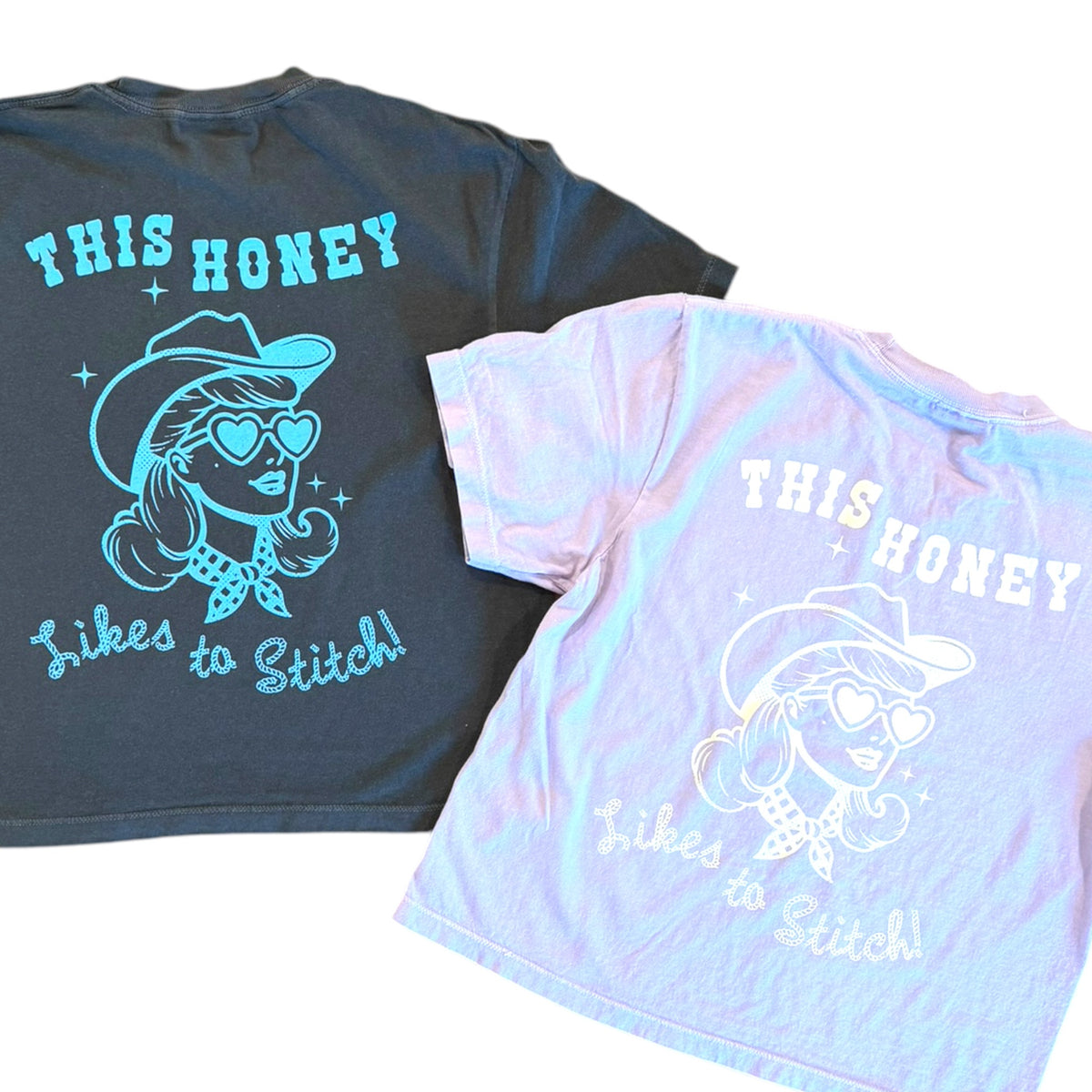 Two graphic t-shirts displayed on a white background, showing the back of each shirt. The left shirt is dark charcoal gray with a bright teal graphic and text reading 'THIS HONEY Likes to Stitch!'.