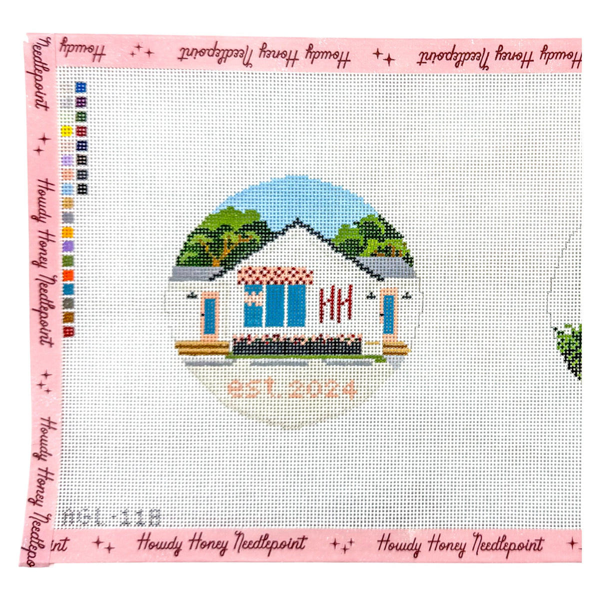 A needlepoint canvas featuring a custom house design with blue windows, green trees, and the text 'EST. 2024' in orange.