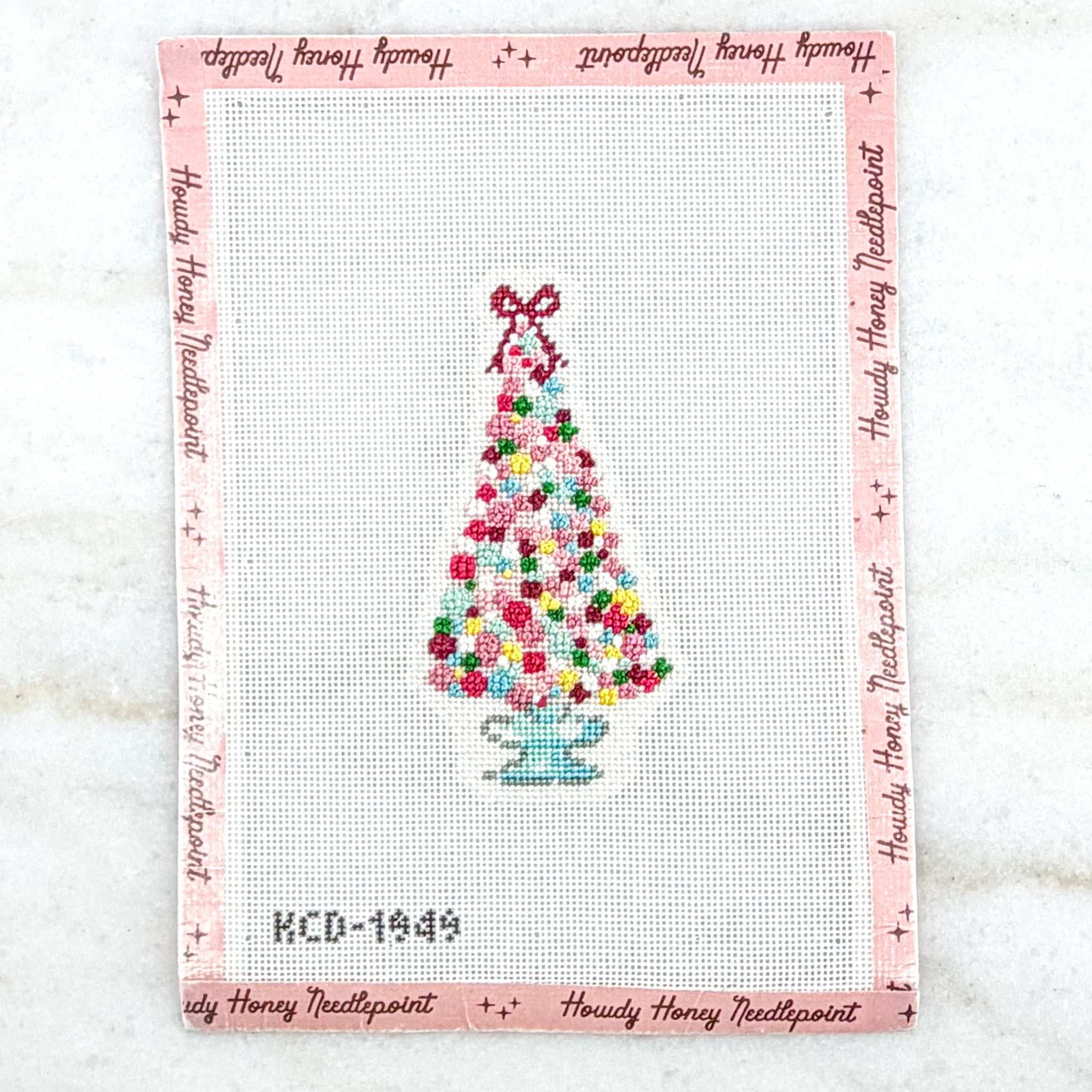 Cross-stitched design of a Christmas tree on a white background with 'Howdy Honey Needlepoint' branding.