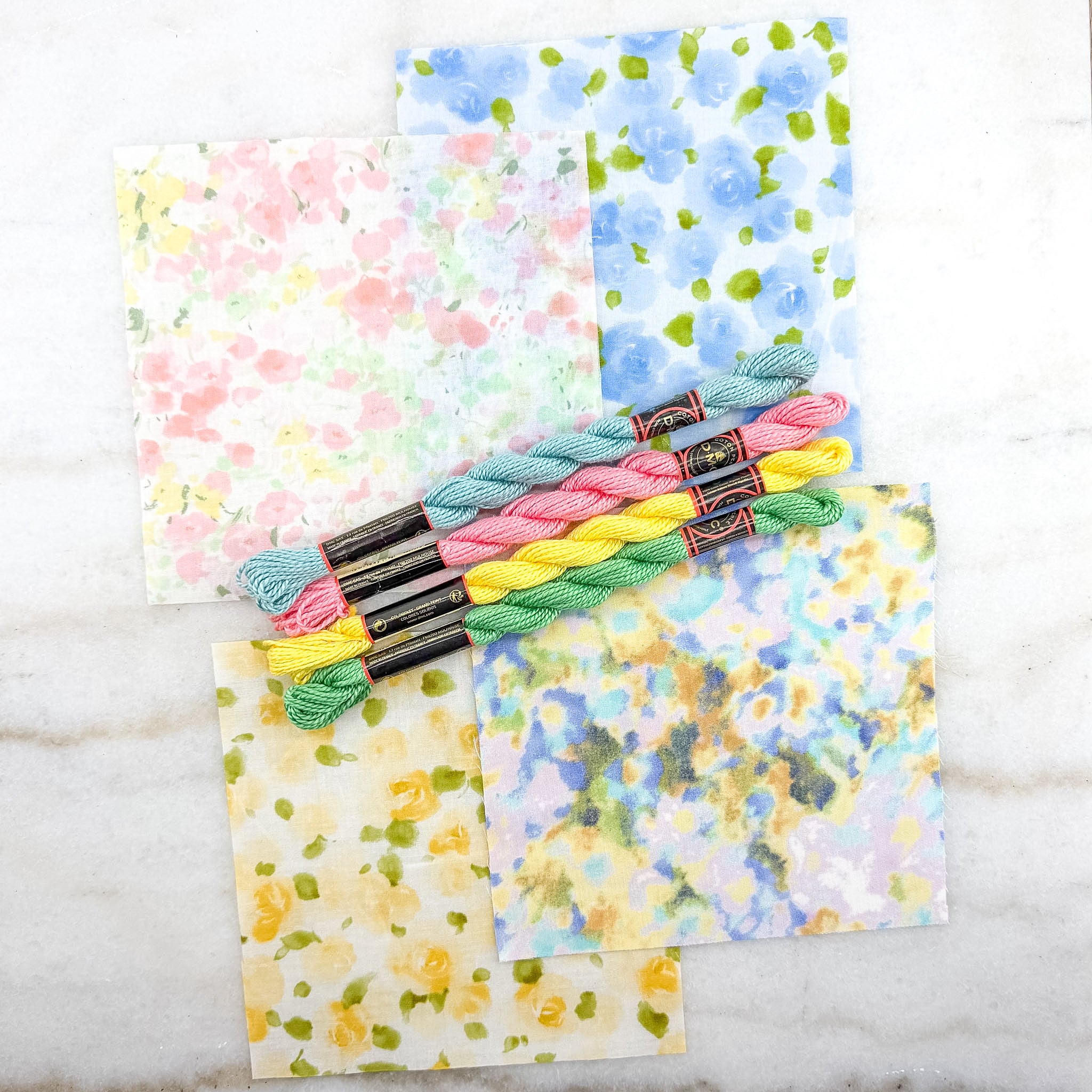 Set of colorful braided yarn with patterned fabric sheets on a marble surface
