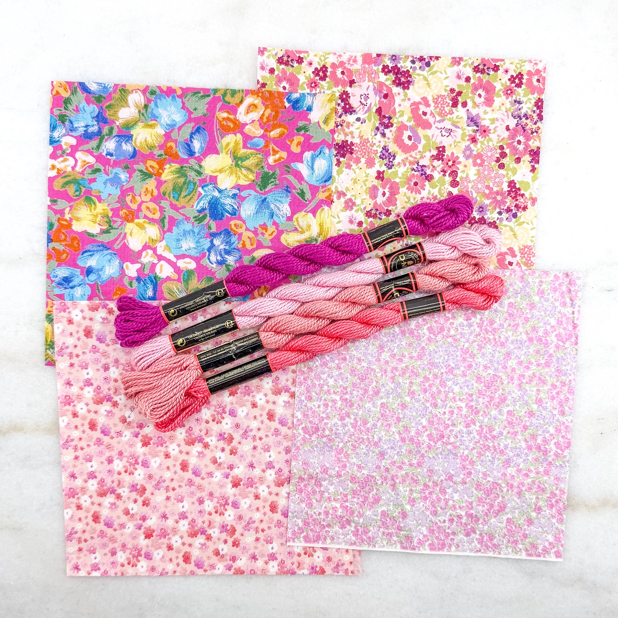 Bundles of pink embroidery floss on floral fabric