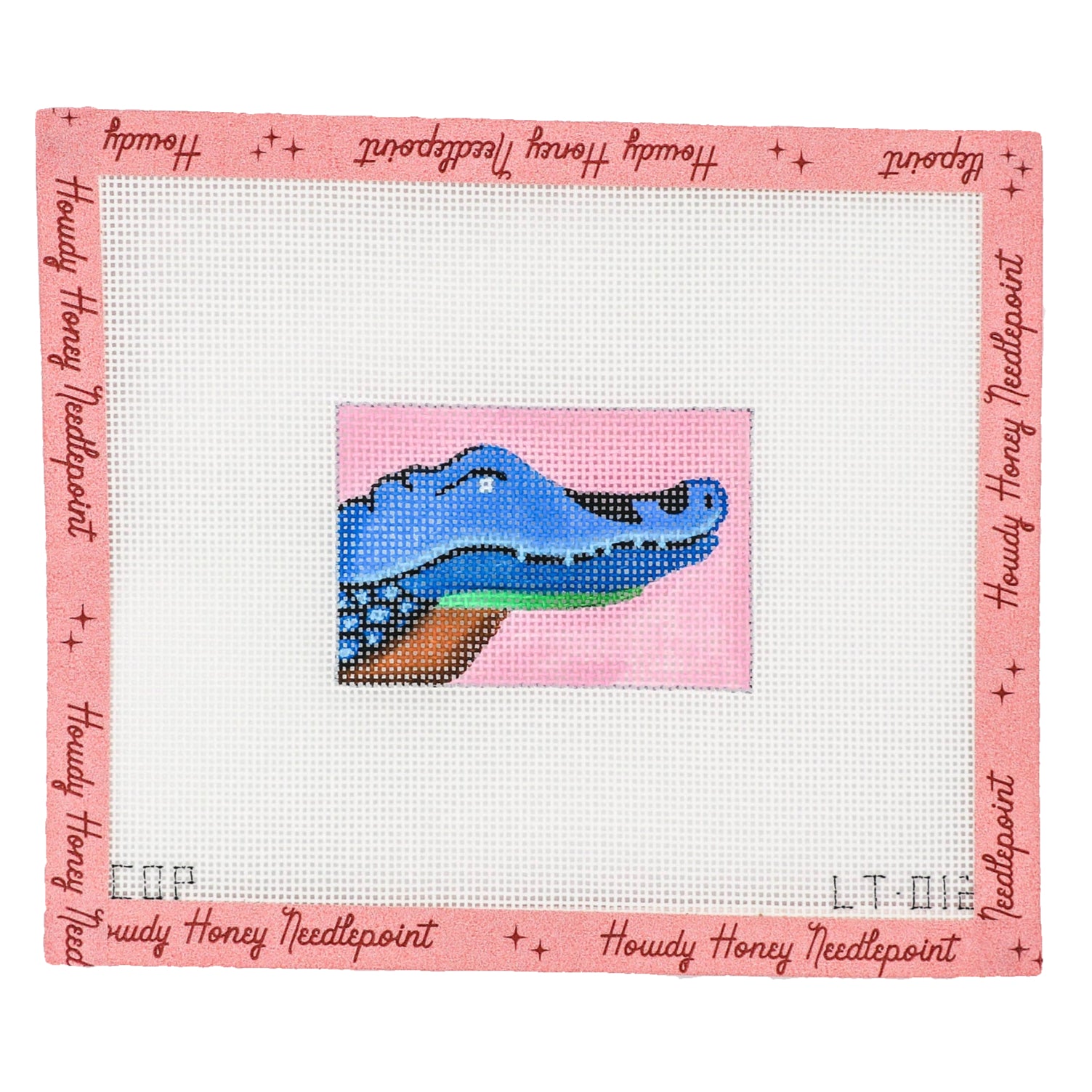 A needlecraft canvas with a blue crocodile design on a pink background, includes a tapestry needle.