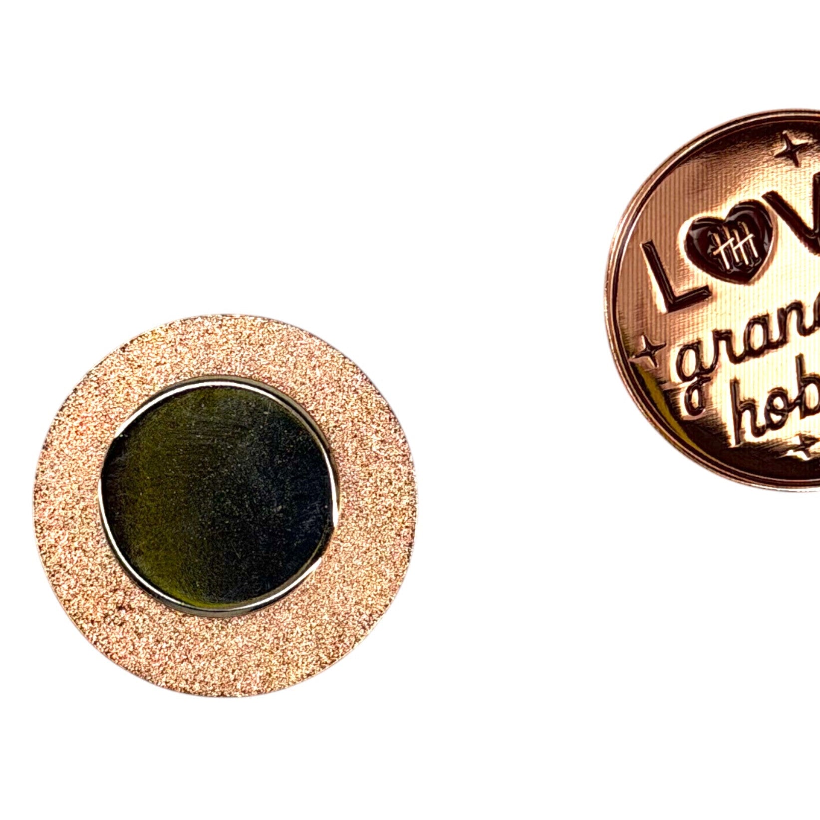 Two round metal pins with engraved text on a white background