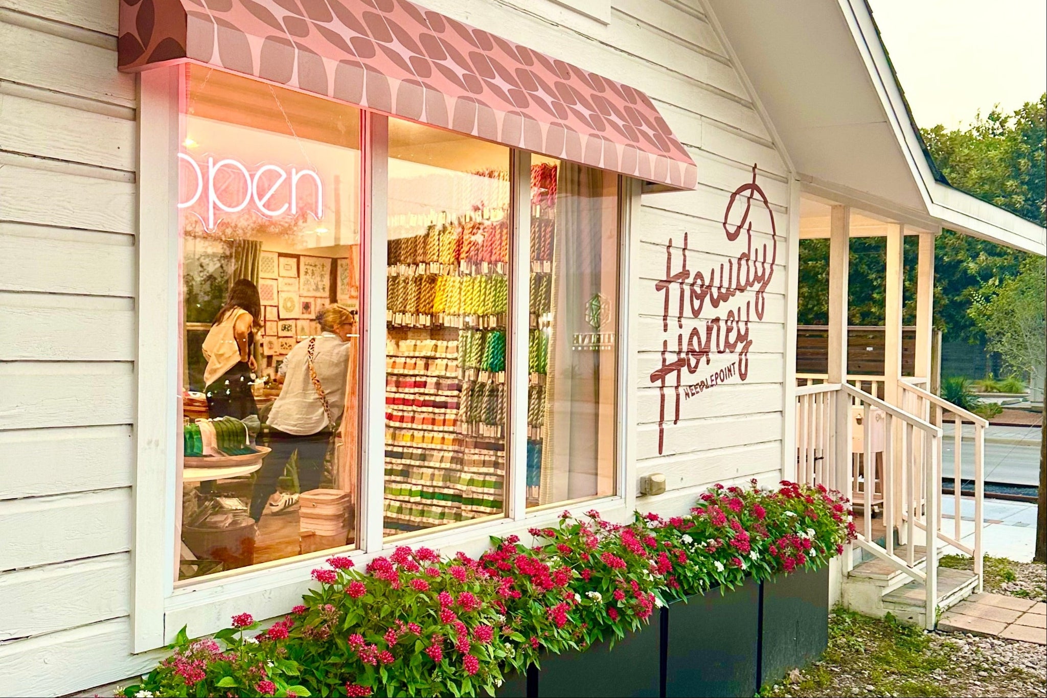 Storefront with 'Howdy Honey' sign, flowers, and 'open' sign.
