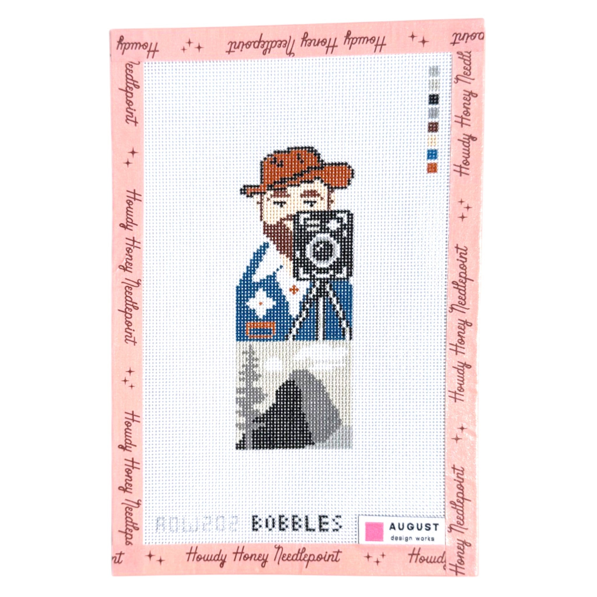 Cross-stitch pattern with a cowboy holding a camera on a white background