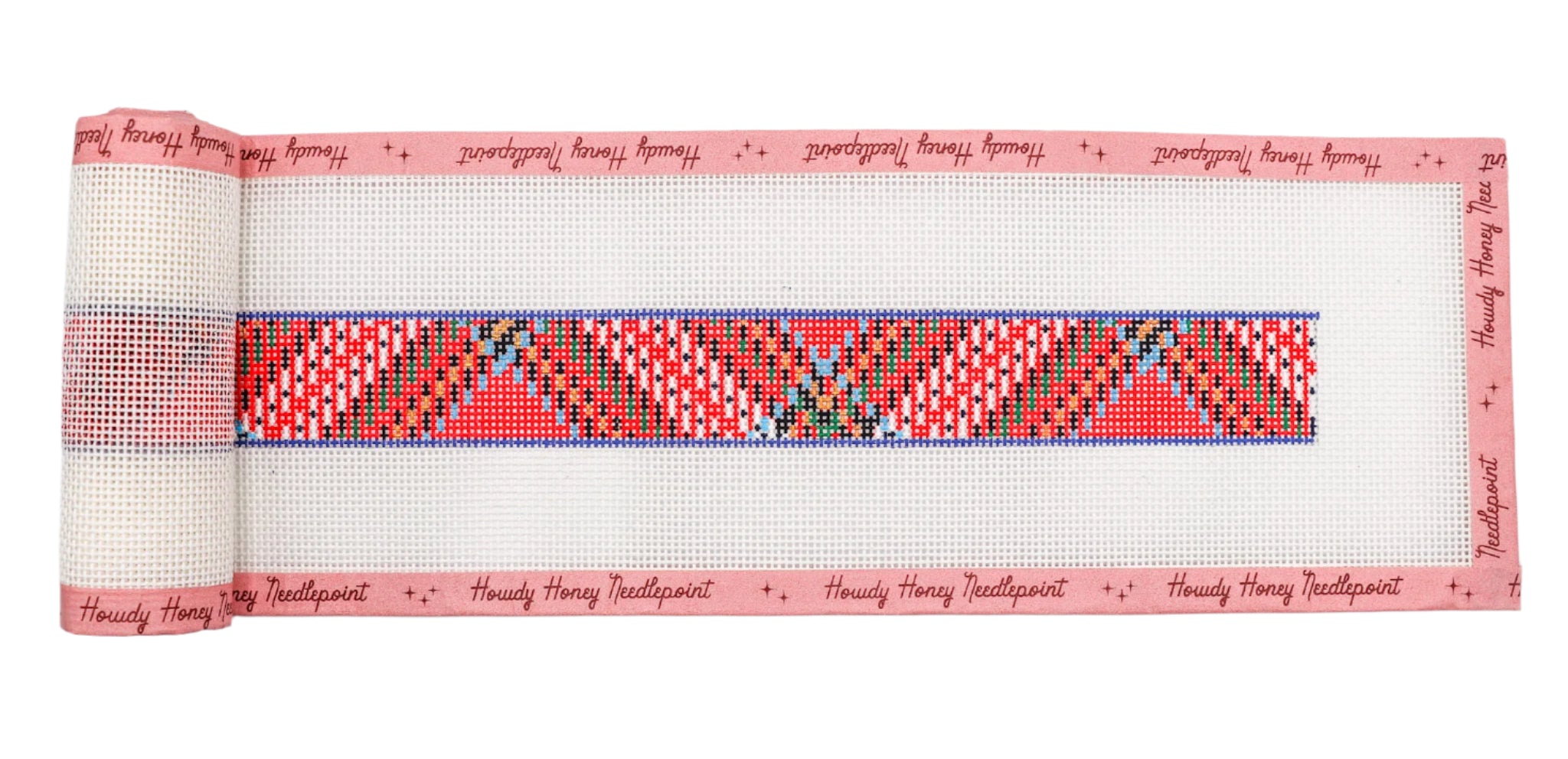 Hand-painted red tartan belt with a pattern of red, blue, and green squares on a white background, rolled with a tapestry needle.