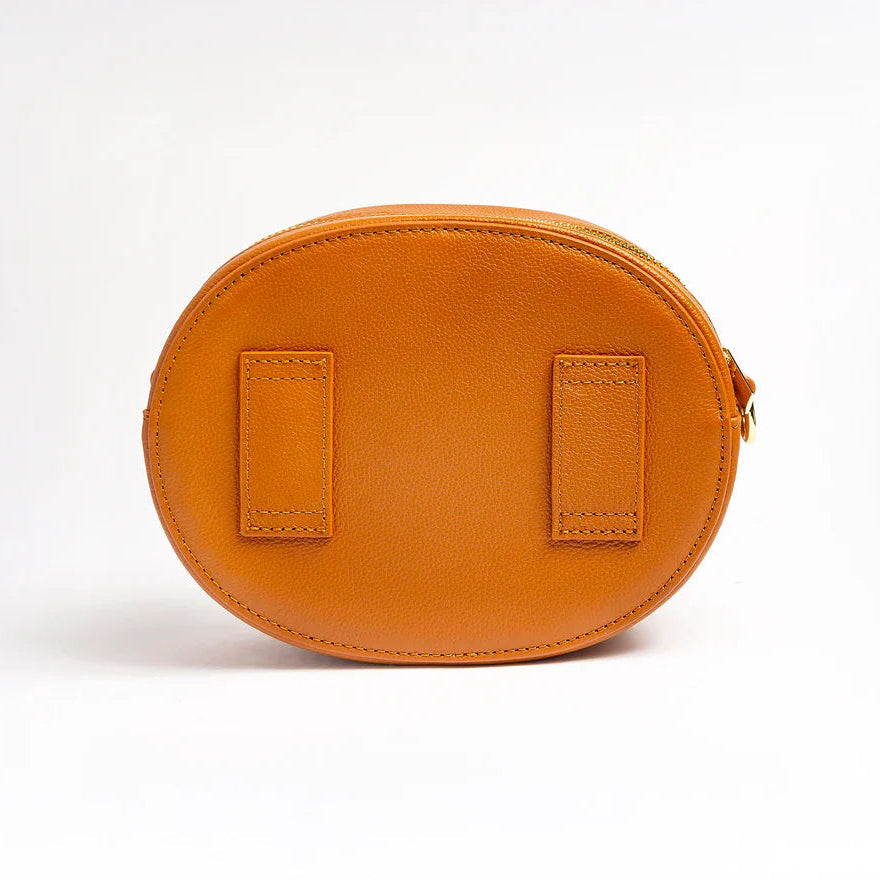 Orange leather bag with two square patches on a white background